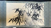 Full view of Chinese hanging scroll painting showing bamboo and mountain landscape in black ink and watercolor on paper with blue fabric border.
