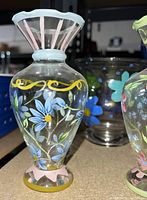 Front view of the first vase with blue floral design and pink and white flared rim.