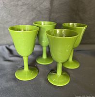 Four mid-century modern lime green glass wine goblets, showing their color, size and shape