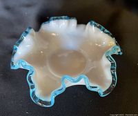 Top angled view of white milk glass candy dish with aqua crest edge ruffled rim.