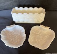 Photo showing all three vintage milk glass dishes: a rectangular grape paneled Westmoreland dish, a grape shaped dish, and an apple shaped dish with flower relief.