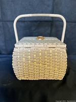 Front view of rectangular vintage wicker sewing yarn basket with single handle and double lid.