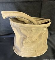 Side view of khaki canvas feed bag showing collapsed state and general wear.
