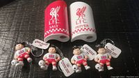 Top view of Liverpool FC red salt shaker and white pepper shaker, with four England Soccer Lil' Brats soccer player keychains arranged below