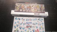 Two 1000-piece puzzles from HEYE: The Smurfs with multiple Smurf characters and Bike Art depicting cyclists. Both puzzles assembled with one missing piece each.
