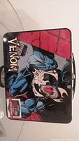 Front view of Venom metal lunchbox showing character artwork and Fan Expo 2018 Exclusive badge