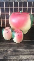 Photo showing vintage apple-shaped ceramic cookie jar with matching large apple salt and pepper shakers on wooden surface.
