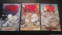Three Bone graphic novels volumes 1, 2 and 4 showing full front covers with colorful cartoon art and titles visible.