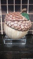 Front and side view of the ceramic acorn-shaped cookie jar showing detailed textured acorn cap and leaf decoration