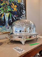 Front-three-quarter view of the venison warmer showing domed lid with embossed decoration, beaded rim, and decorative feet