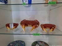 Three crab dishes displayed on glass shelf: one large center, two small flanking