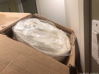 Opened box showing rolled white gel foam mattress inside plastic sleeve.