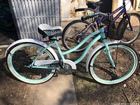 Side view of turquoise and white beach cruiser bike with patterned seat and chain guard