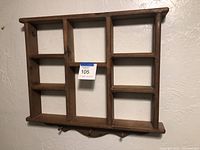Photo of one of the small wooden hanging shelf units with multiple compartments, showing wood finish and structure.