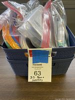 Photo showing blue plastic bin filled with bags of multicolored filament coils and other materials for 3D pen.
