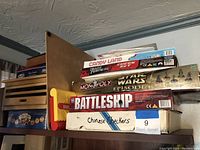 Shelf stacked with board games including Candy Land, Monopoly Star Wars, Battleship, Chinese Checkers