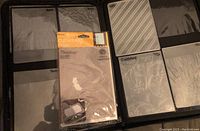 Photo shows a large binder containing multiple clear plastic embossing folders with various intricate patterns. Included is a packaged 'Anna Griffin' Cuttlebug embossing folder with a cat shape design.