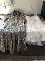 Grey polka dot dress and white sheer dress together laid flat on a surface