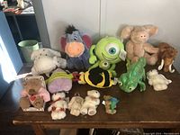 Full view of eleven assorted plush toys on a wooden surface