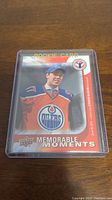 Front of Connor McDavid rookie card showing player image and text 'Rookie Card' and 'Memorable Moments' in Edmonton Oilers uniform.