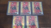 Five Tim Stutzle rookie hockey cards arranged in rows on a wooden surface, each card in clear protective sleeve showing holographic finish and Stutzle in Ottawa Senators red jersey.