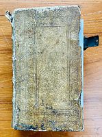 Worn leather cover of 1835 German prayer book with embossed decorations and missing brass bracket.
