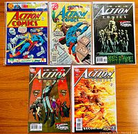 Five Action Comics comic books laid out with visible colorful covers featuring Superman and other characters from different eras.