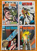 Four Batman comic books laid out flat, showing front covers including issue 397 with Two-Face cover, 410, 414, and 424 issues.