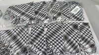 10 black and white square neckerchiefs neatly arranged, all individually wrapped in plastic packaging.