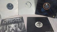 Five vinyl records in white and black sleeves laid out flat.