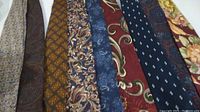 Front view of all nine ties laid out side by side, showing various colors and patterns including paisley, floral, geometric, and solid designs.