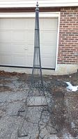 Full view of the 74-inch tall metal Eiffel Tower styled outdoor decor against a garage door, showing overall structure and condition.
