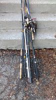 Photo of tangled fishing rods and reels on steps showing wear and some broken tips