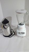 Photo shows the Sunbeam electric kettle with a stainless steel body beside the Sunbeam blender with a glass pitcher on a white base. Both appliances are placed on a white surface.
