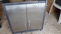 Front view of Mastercraft metal tool cabinet showing diamond plate double doors with handles and lock, black frame, and caster wheels.