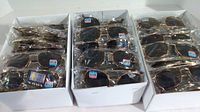 Three boxes each containing 24 pairs of identical aviator style sunglasses, all individually wrapped in plastic.