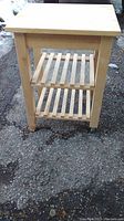 Front view of the wood butcher block table showing its structure and two shelves.