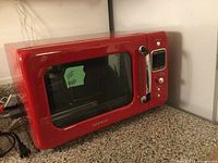 Closed red Daewoo microwave with front view showing the door, chrome handle, and control panel.