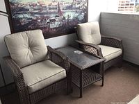 Two wicker armchairs flanking a coffee table with glass top and lower wicker shelf