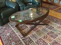 Front-angle view showing overall shape, frame finish, X-style support and inset glass top