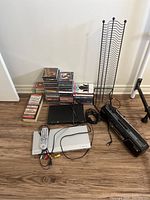 Wide view showing JVC and Sony DVD players, cassette player, stacks of DVDs, CDs, tapes and a black metal vertical disc rack
