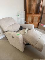 Full view of the electric power recliner chair extended to a reclined position, beige fabric upholstery visible.