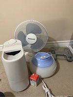 Photo showing the white Honeywell tabletop rotating fan, small humidifier with top lid, larger round humidifier, red box, and a glass digital bathroom scale.
