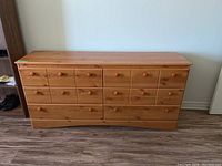 Front view of six drawer dresser with knob handles and knotty pine veneer finish.