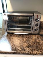 Front view showing Black & Decker logo, door with window, and control knobs on the right.