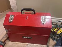 Closed red metal Husky toolbox with black handle and silver latches, showing exterior condition.