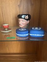 Display shelf with two blue Wedgwood jasperware jewellery boxes and a Royal Doulton Monty character jug stein