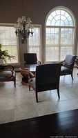 Four armchairs arranged around round coffee table under chandelier, showing overall set and style.