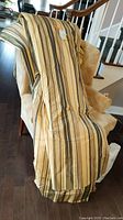Four folded striped custom pinch pleat drapery panels draped over a chair, showing fabric pattern and length.