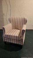 Full view of the striped JoFran stuffed armchair showing the shape, upholstery pattern, nailhead detailing, and legs.